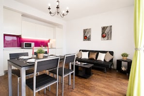 A modern living space with a dining area, a black sofa, and artwork on the walls.