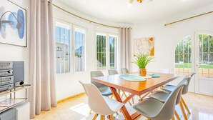 Una habitación amplia con una gran mesa de madera y sillas alrededor, ventanas grandes y vistas al exterior.