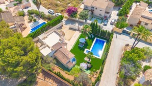 Vista aérea de una zona residencial con dos piscinas, un césped cuidado y casas circundantes.