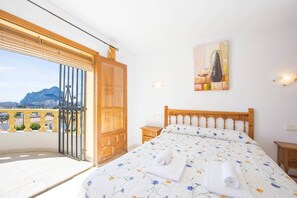 Een slaapkamer met een groot bed, een houten deur, uitzicht op de stad en een schilderij aan de muur.