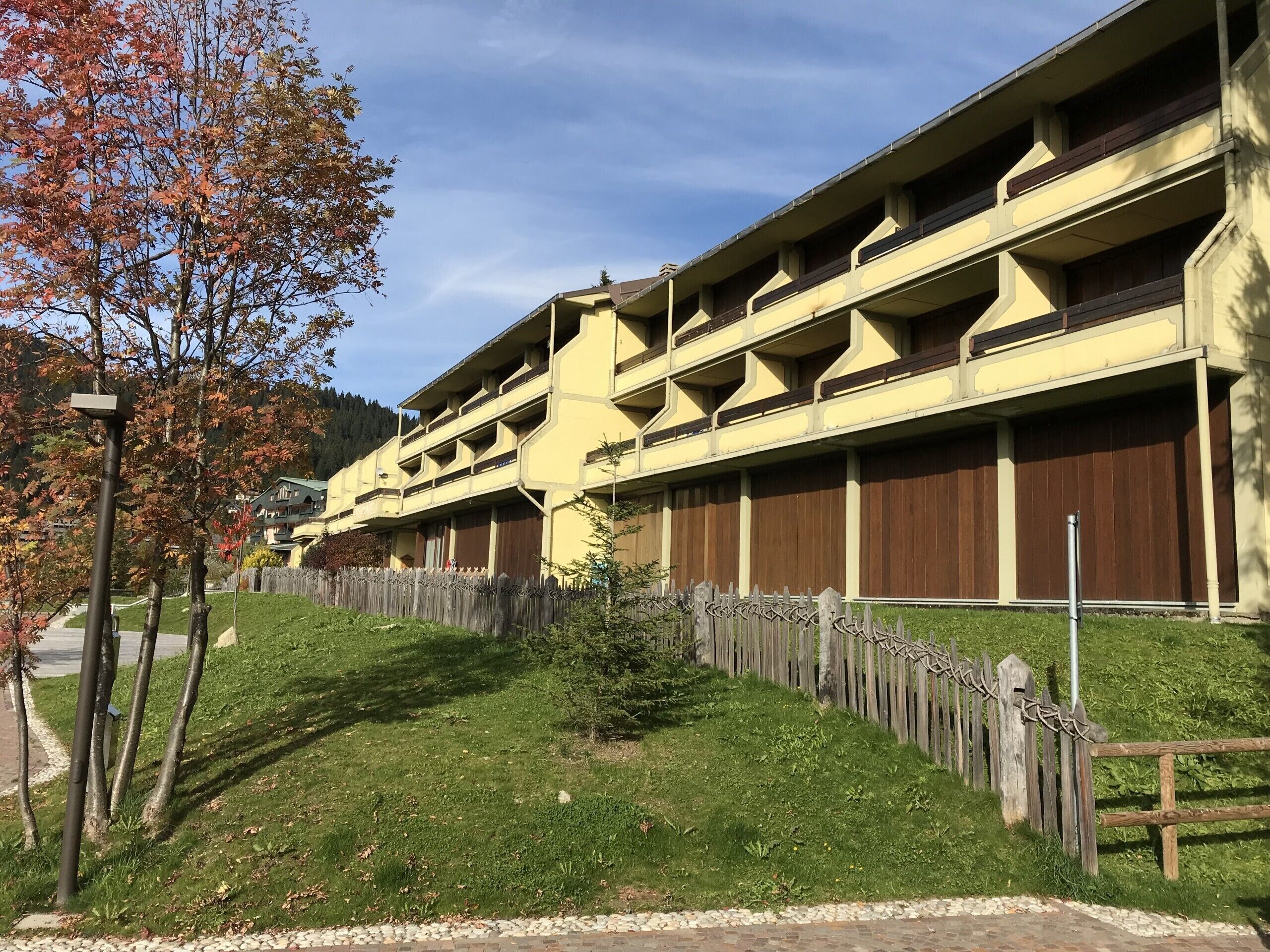 A multi-story building with a yellow facade and wooden balconies.