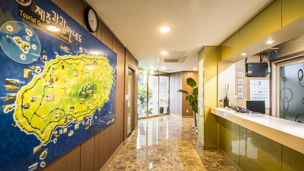 A hotel lobby with a large map on the wall, a reception desk, and a plant. - Champion Hotel Jeju (Jeju City)