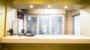 A reception desk with a calendar, a telephone, and a small table with a vase and candles. - Champion Hotel Jeju (Jeju City)