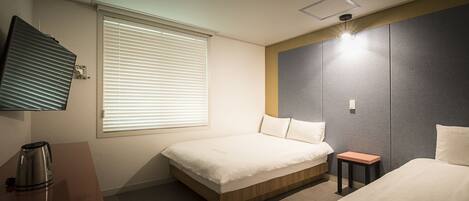 A hotel room with a bed, a small table, a coffee maker, and a TV mounted on the wall.