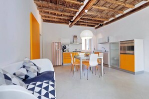 A modern kitchen with white cabinets, a dining area with a table and chairs, and a sofa with patterned cushions. - Rome, historical center, characteristic apartment up to 5 people (Roma)