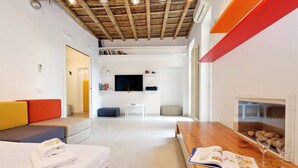 A modern hotel room with a wooden ceiling, a flat-screen TV, a sofa, a dining table, and a fireplace. - Rome, historical center, characteristic apartment up to 5 people (Roma)