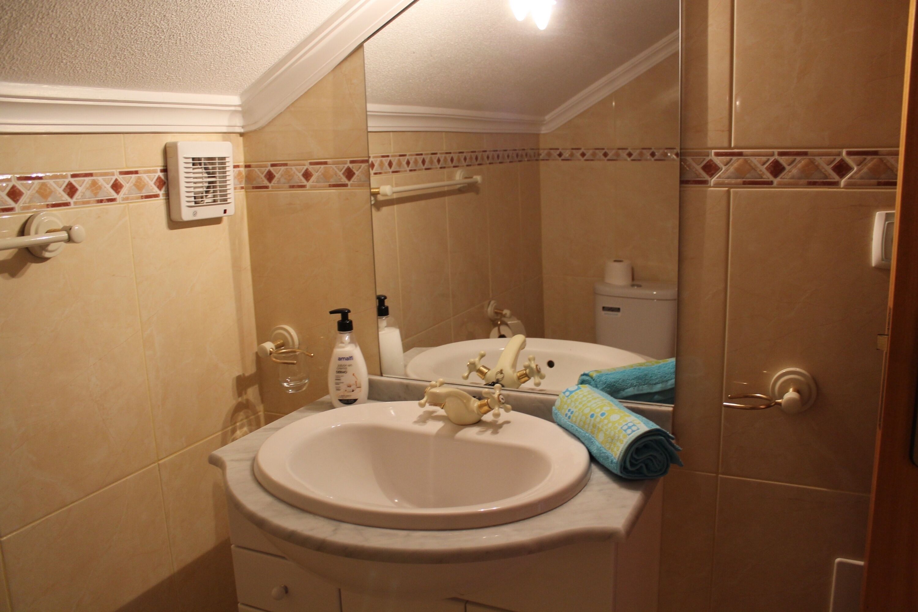 Een badkamer met een wastafel, spiegel, handdoekhouder en toiletartikelen.