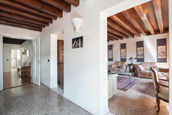 A spacious living area with a high ceiling, wooden beams, and a seating area with a sofa and chairs.