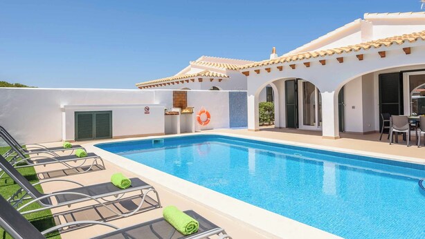 En swimmingpool med liggestole og en overdækket terrasse.