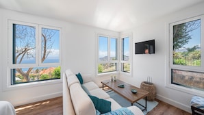 A modern living room with a large sofa, a wooden coffee table, and a TV mounted on the wall. - Funchal Character Villa, Seaview | Quinta Alegria (Funchal)