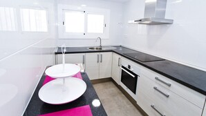 A modern kitchen with white cabinets, a black countertop, a stainless steel sink, and a window above the sink.