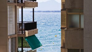 A high-rise building with balconies overlooking a body of water and a distant mountain range.