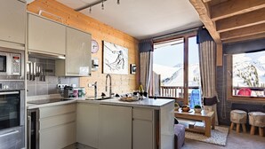 Et moderne køkken med hvide skabe, rustfrie stålgrebe og et træloft.