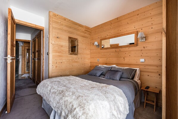 Un dormitorio con una cama grande, paredes de madera, un espejo y una mesita de noche pequeña.