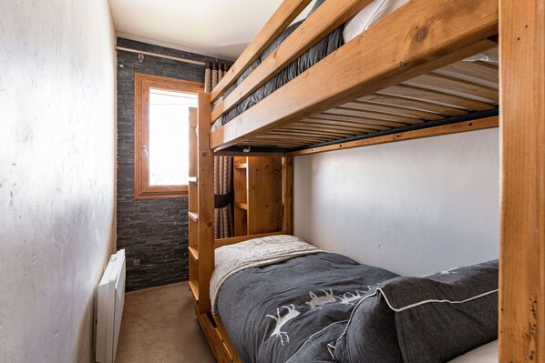 A bunk bed room with a window, a radiator, and a brick wall.
