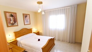 Un dormitorio con una cama de madera, mesitas de noche, una lámpara y una ventana con cortinas.
