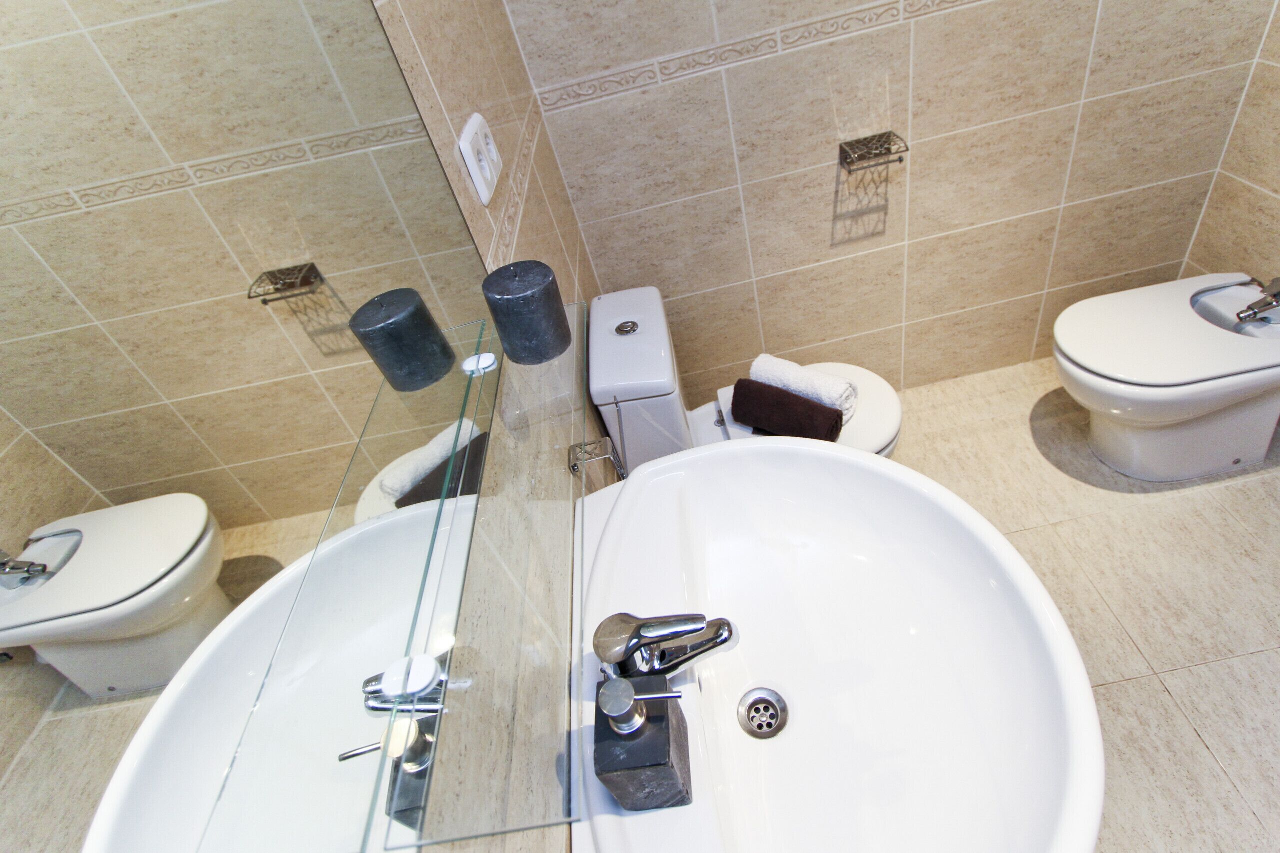 Ein Badezimmer mit einem weißen Waschbecken, zwei Toiletten und einer Duschkabine aus Glas.