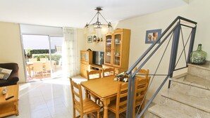 Un comedor con una mesa y sillas de madera, un televisor y un aparador con puertas de cristal.
