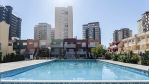 Une piscine dont le bord est recouvert de carreaux, entourée d’immeubles résidentiels à plusieurs étages.