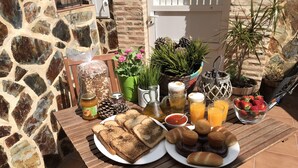 Une table de petit-déjeuner avec des tartines, des muffins et des fruits, ainsi que des condiments et des boissons.