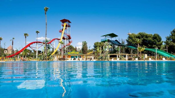 A swimming pool with a water slide and a tower structure. - MAR PINEDA Apartment (La Pineda)