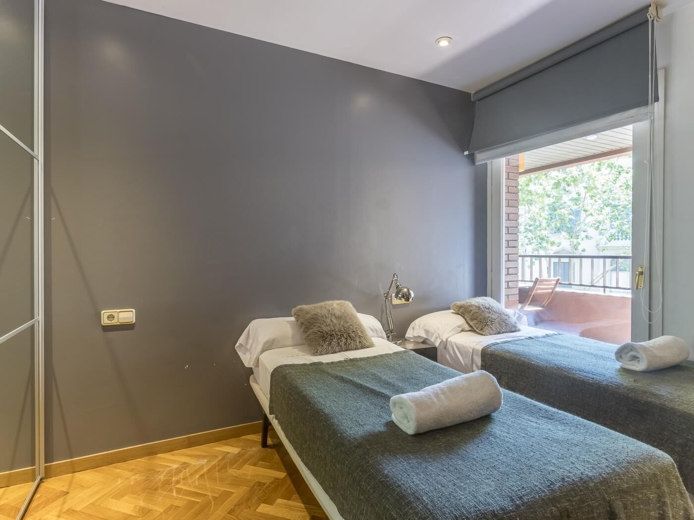 Una habitación con dos camas, una mesita y una ventana que da a un balcón.