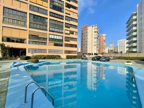 A swimming pool with a metal ladder, surrounded by a paved area with a few parked cars. - ALBAIDA PARK BLUELINE R014 (Benidorm)