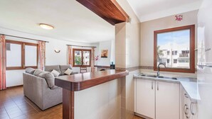 Cozinha moderna com armários brancos, bancada de madeira e janela com vista para edifícios.