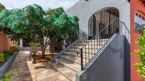 Eine Treppe mit Fliesenmuster, die zu einem Haus mit roter und grauer Fassade führt.