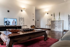 A living room with a wooden coffee table, a television, and a cabinet with decorative items. - Mansarda Magritte (Venice)