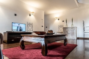 A modern living room with a television, a coffee table, and decorative lighting. - Mansarda Magritte (Venice)