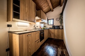 Una cocina con armarios de madera, horno empotrado y ventana.