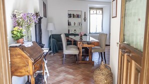 Ein Essbereich mit Holztisch, Stühlen, einem Bücherregal und einem Blumentopf.