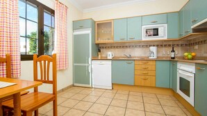 A compact kitchen with teal cabinets, a white refrigerator, a dishwasher, a microwave, and a stove.