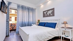 A bedroom with a bed, a bedside table, a lamp, a world map on the wall, and a view of the outside.