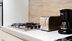 A kitchen with a gas stove, a toaster, and a coffee maker on the counter.