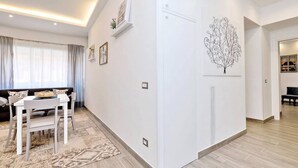 A modern living room with a dining area, a white sofa, a dining table, and a patterned rug.