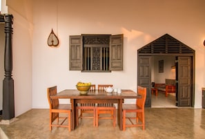 A dining area with a wooden table and chairs, a bowl of fruit, and a decorative wall piece. - Blue Parrot Beach Villa right on beach with privat swimming pool (Ambalangoda)