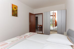 Ein Schlafzimmer mit Bett, Kleiderschrank und einem Sonnenblumenbild an der Wand.