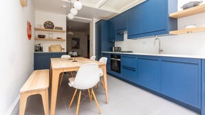 A modern kitchen with blue cabinets, a wooden dining table, and white chairs.