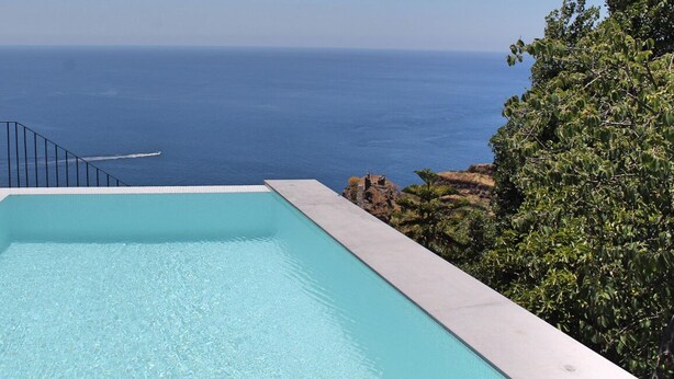 Ein rechteckiger Infinity-Pool mit klarem, blauem Wasser, umgeben von einem hellen Deck.