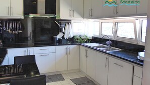 Eine moderne Küche mit weißen Schränken, einer schwarzen Arbeitsplatte und einem Fenster, das für natürliches Licht sorgt.