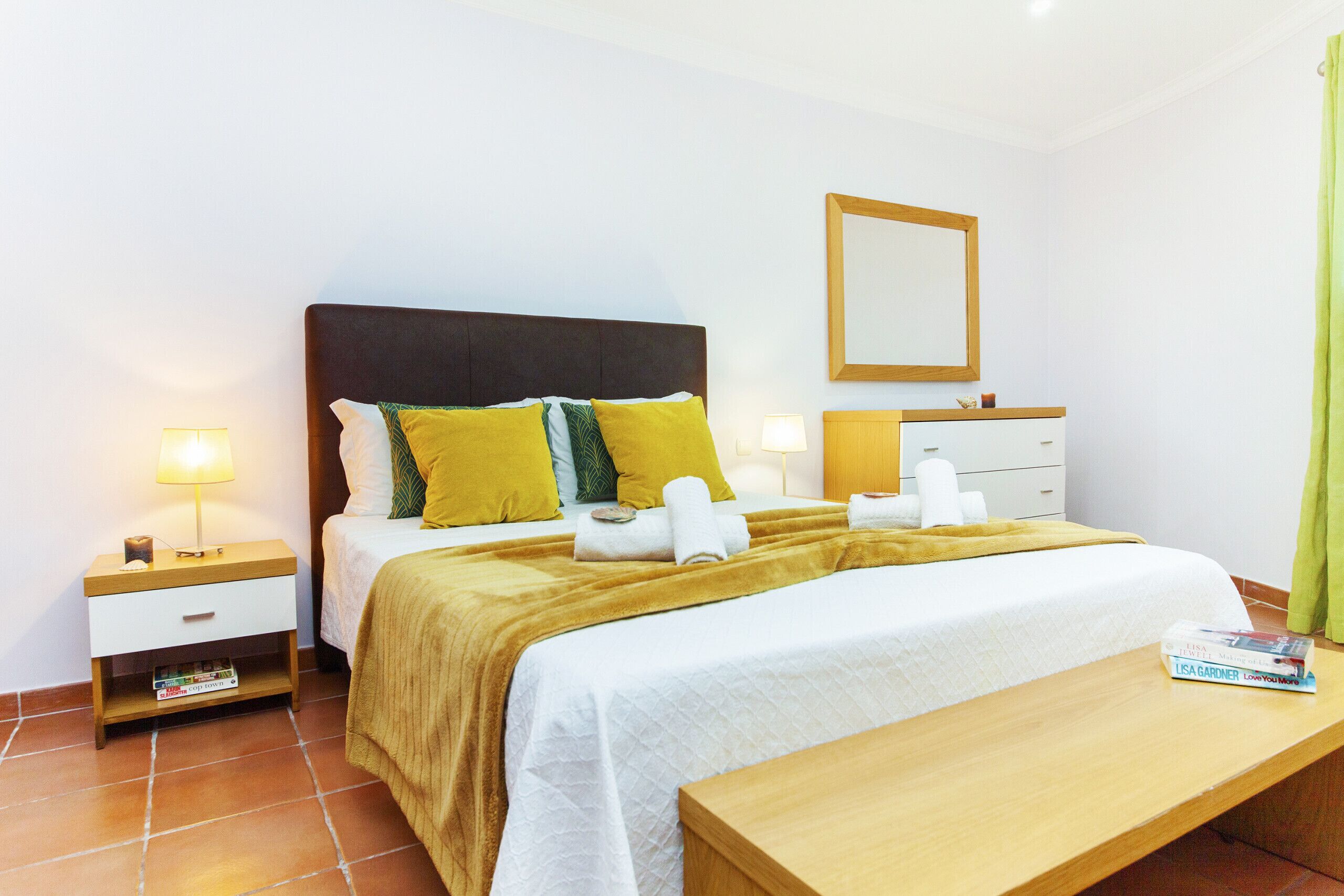 A hotel room with a bed, bedside tables, a mirror, and a bedside lamp.