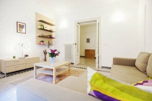 A modern living room with a sofa, a coffee table, a cabinet with shelves, and a radiator. - Rome - Spacious apartment near the historic center (Rome)