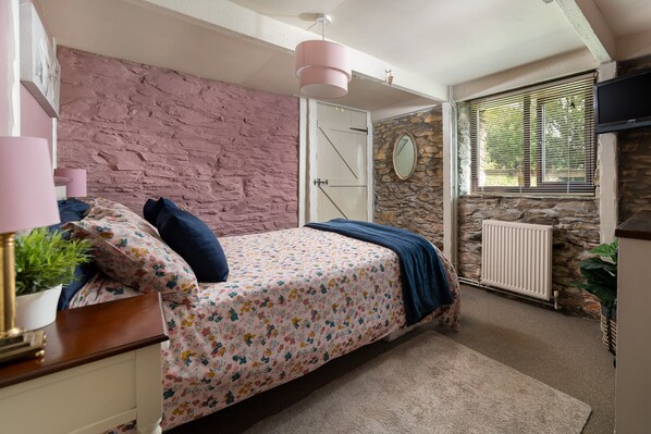 A bedroom with a bed, a dresser, a mirror, a radiator, and a window with blinds. - Two-bedroom, pet friendly holiday cottage set in Fowey and within walking distance of the beach (Fowey)