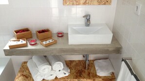 Un bagno con un mobile contenitore in legno, un lavandino bianco e una vasca da bagno nera.