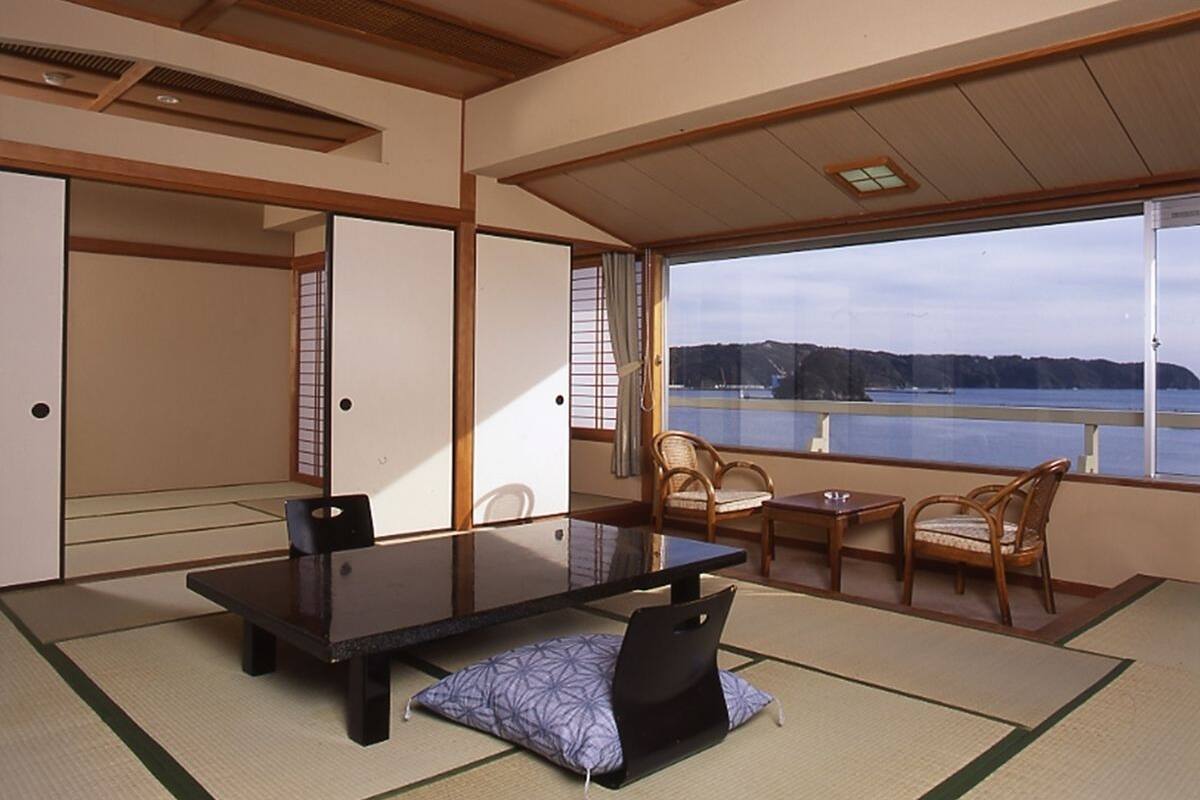 Ein traditioneller japanischer Raum mit Tatami-Böden, einem niedrigen Tisch und Blick auf einen See.
