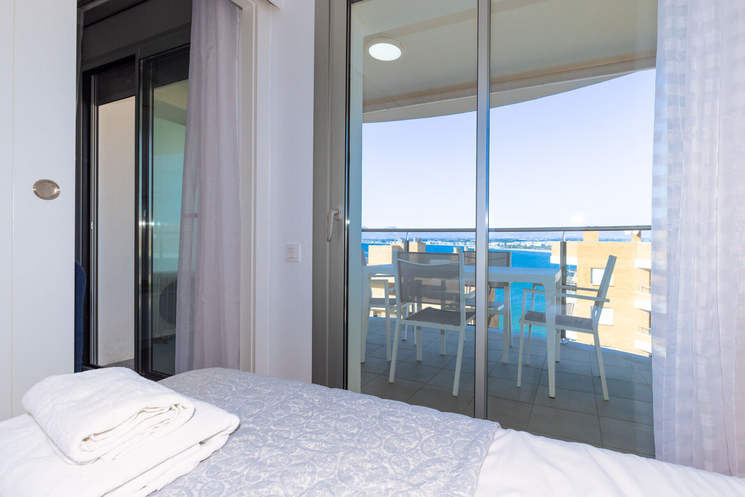 Ein Hotelzimmer mit Bett, einem Balkon mit Tisch und Stühlen und Blick auf die Stadt.