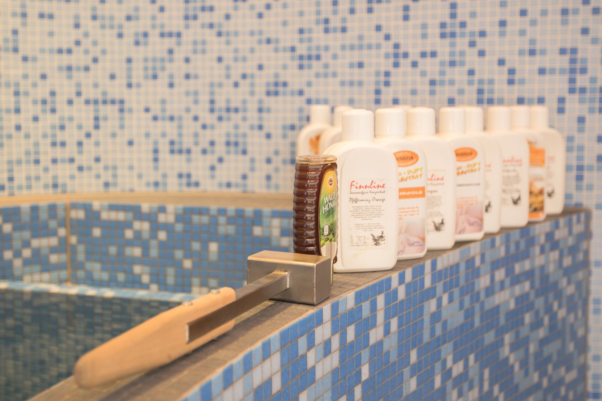 A row of toiletries on a tiled ledge in a bathroom.