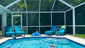 En pool med kristallklart blått vatten, omgiven av ett takförsett område med blå solstolar.